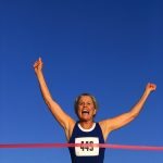 Runner Crossing the Red Tape at the Finish Line