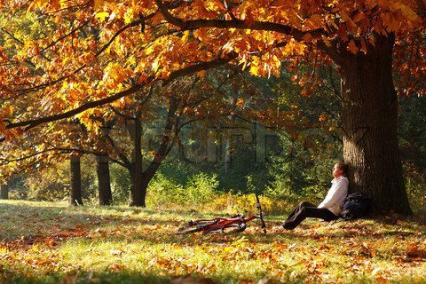 Woman cyclist relaxing in autumn park