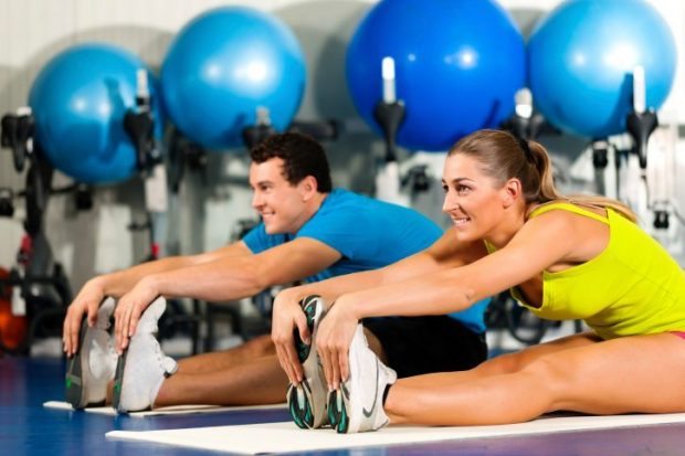 Couple Exercising Stretching at the Gym