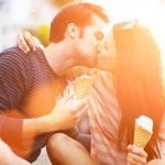 romantic couple kissing while holding ice cream