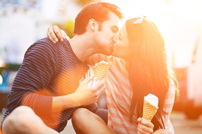 romantic couple kissing while holding ice cream